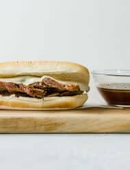 Slow Cooker French Dip Sandwiches with a cup of au juice next to the sandwich.