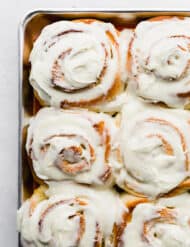A close up photo of homemade orange rolls covered in frosting.