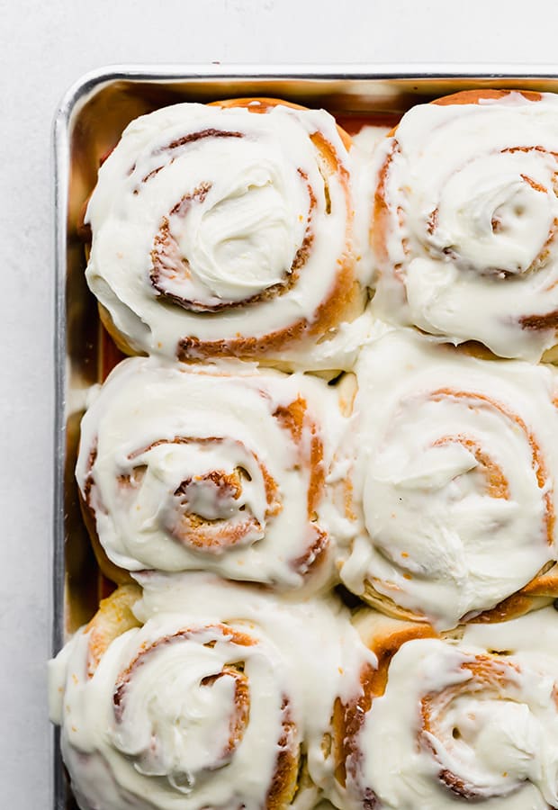 A close up photo of homemade orange rolls covered in frosting.