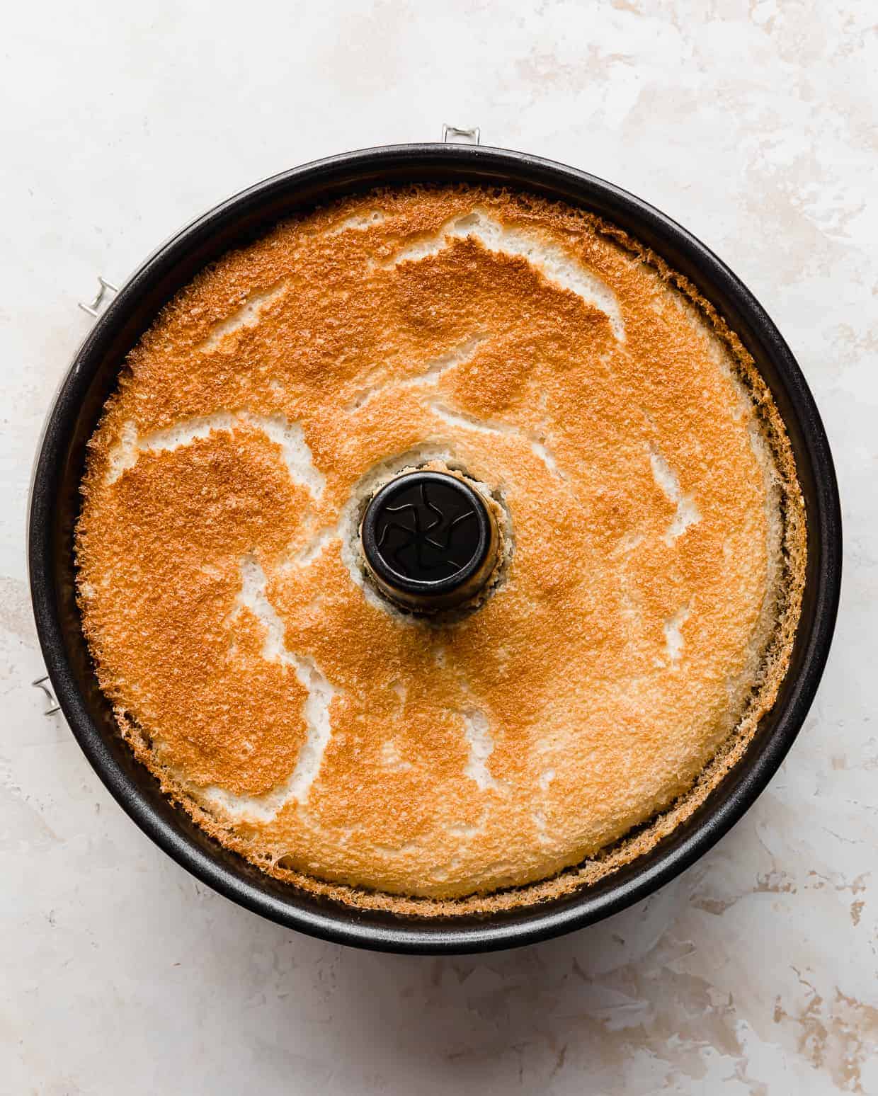 A golden brown baked Angel food cake in a tube pan.