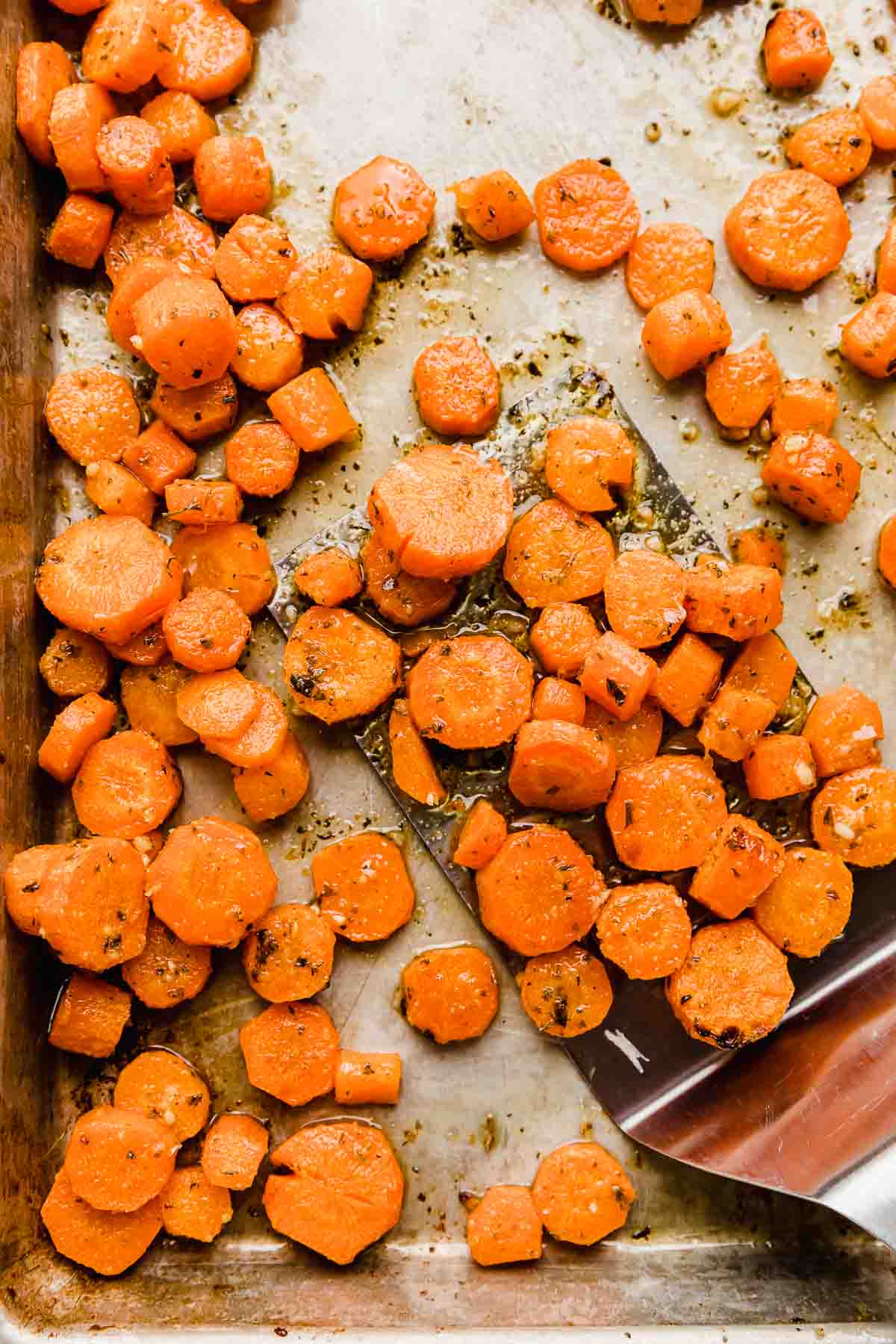 Garlic parmesan roasted carrots sliced into coins, on a baking sheet.