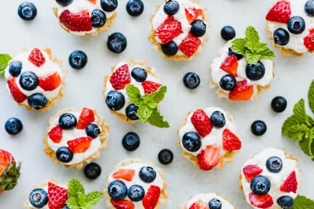 Overhead view of Greek yogurt whipped cream in Fillo shells topped with chopped strawberries and blueberries garnished with mint.