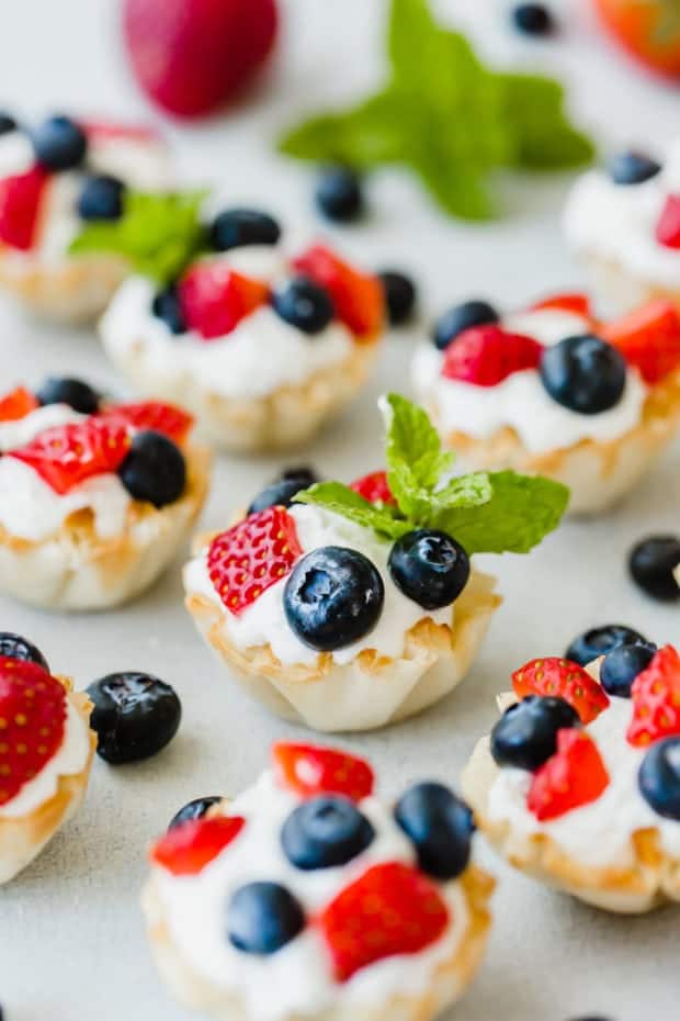 Fillo shells filled with greek yogurt whipped cream and topped with chopped strawberries and blueberries.