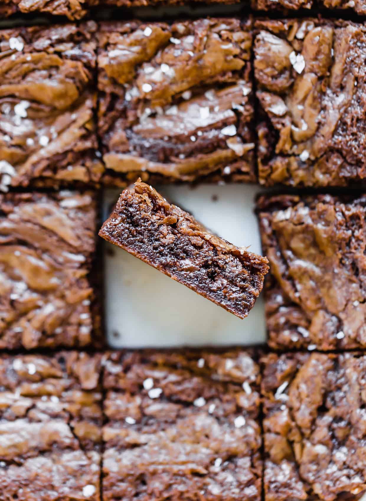 Overhead view of Nutella brownies cut into squares, with one brownie tilted towards the camera to show the thickness of the brownie.