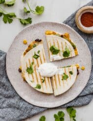 Top view of a 6 inch grilled quesadilla topped with chopped cilantro and a dollop of sour cream.