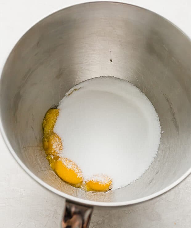 A bowl with sugar and egg yolks in it.