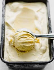 An ice cream scoop scooping out a portion of homemade vanilla ice cream.