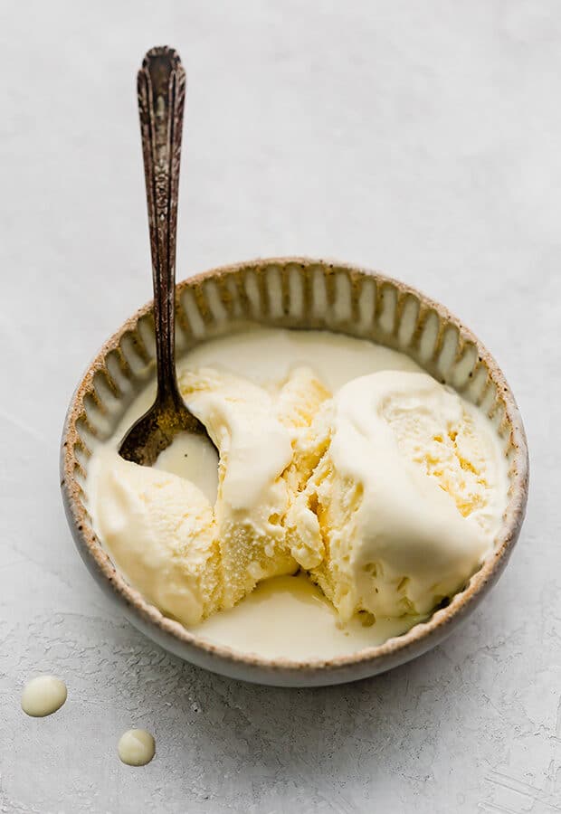 A bowl full of homemade vanilla ice cream and a spoon sitting in the bowl.