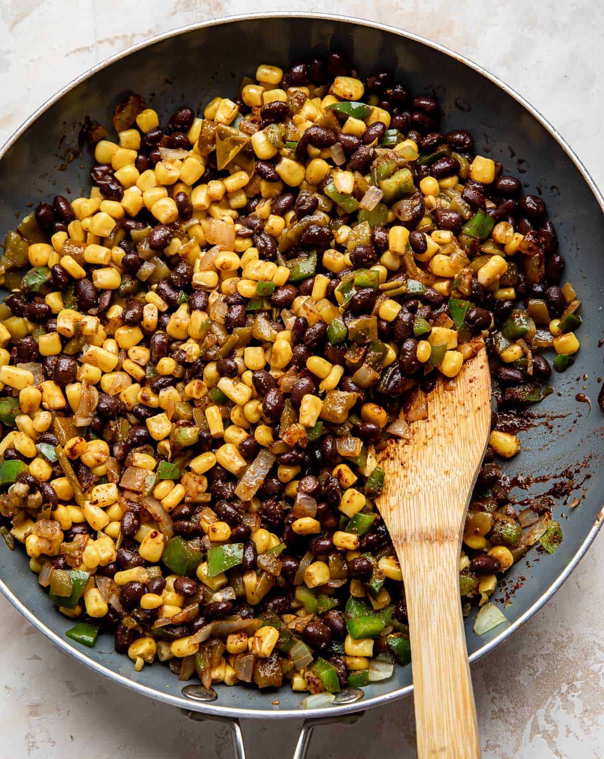 A close up of corn, black bean, and pepper mixture in a gray skillet.