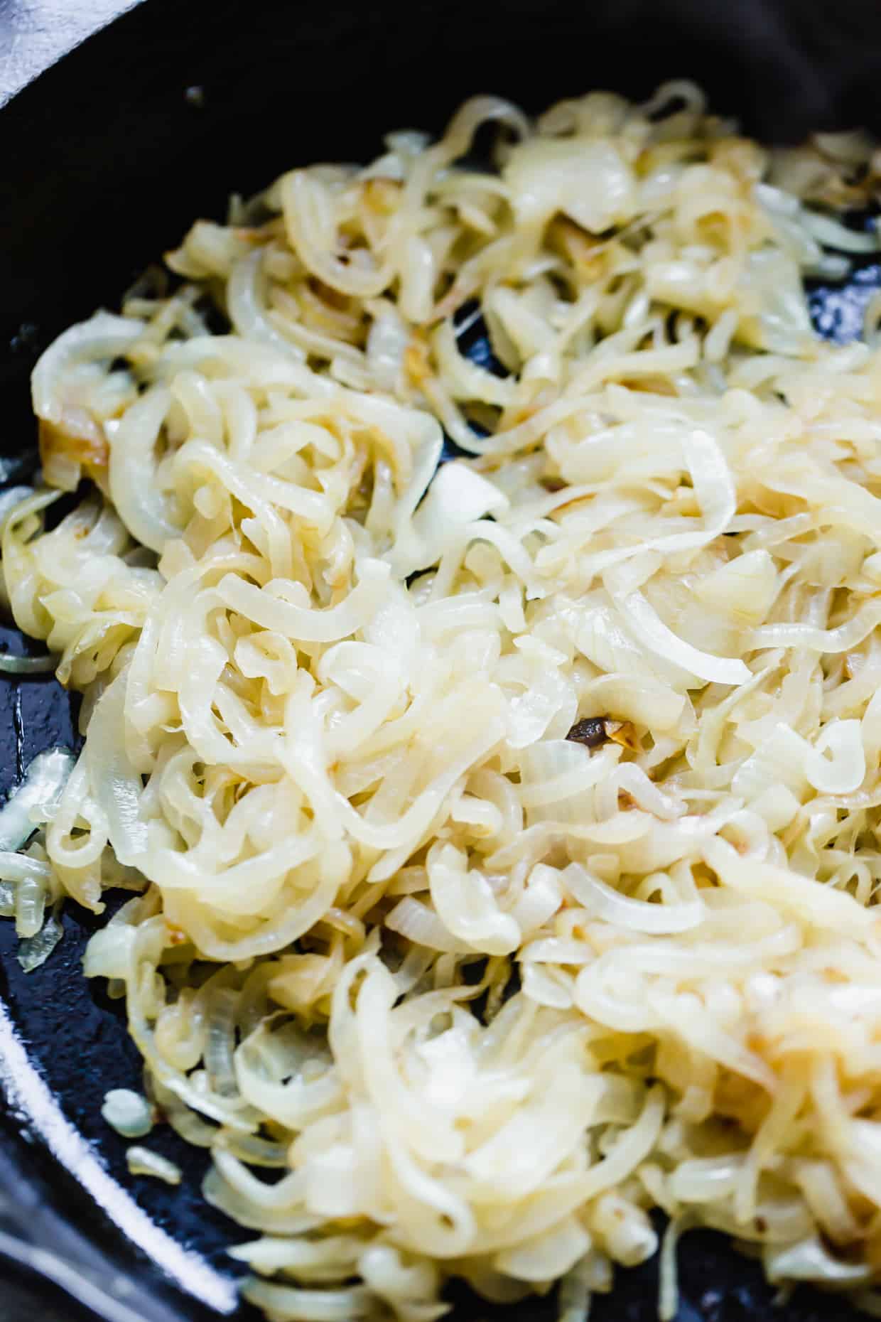 Partially caramelized onions in a black skillet.