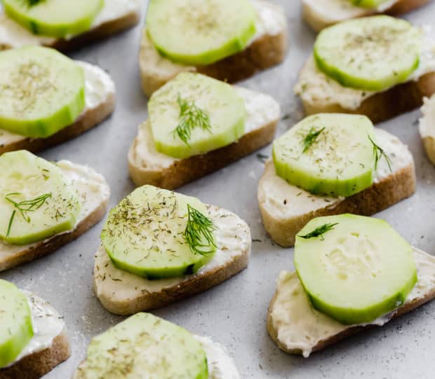 Sliced baguettes layered with a cream cheese spread and sliced cucumber.