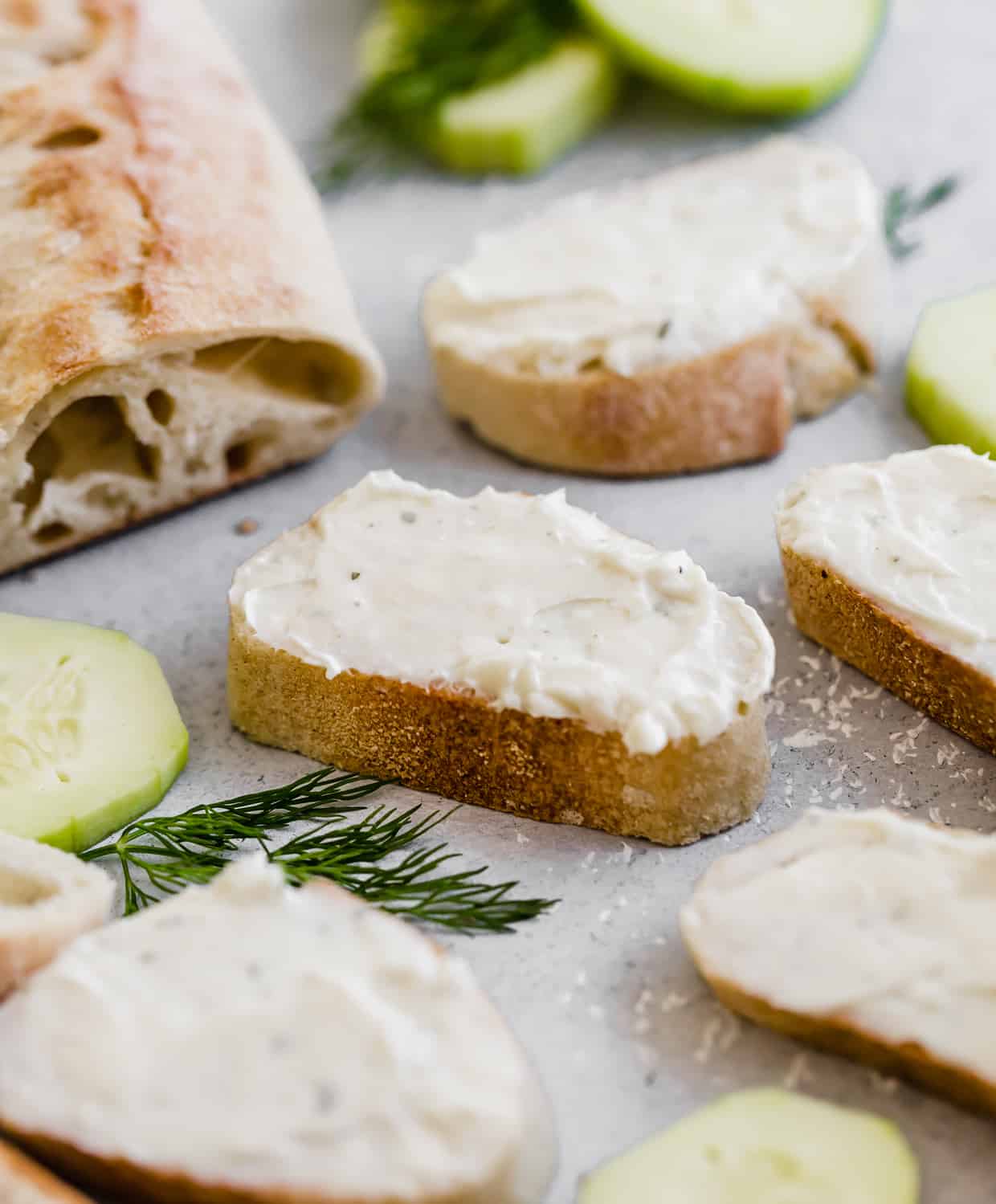 Sliced baguette with cream cheese mixture spread over the sliced bread.