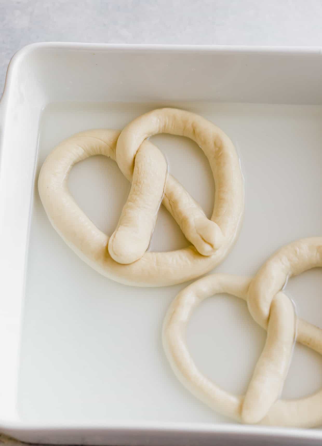An unbaked pretzel in a baking soda and water bath.