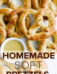 Homemade pretzels baked to golden brown, stacked in a heap with a bowl of honey mustard in the midst of the pretzels.