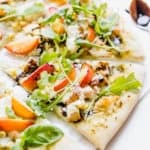 Slice of pizza topped with diced chicken, corn, nectarines, ricotta, and arugula.