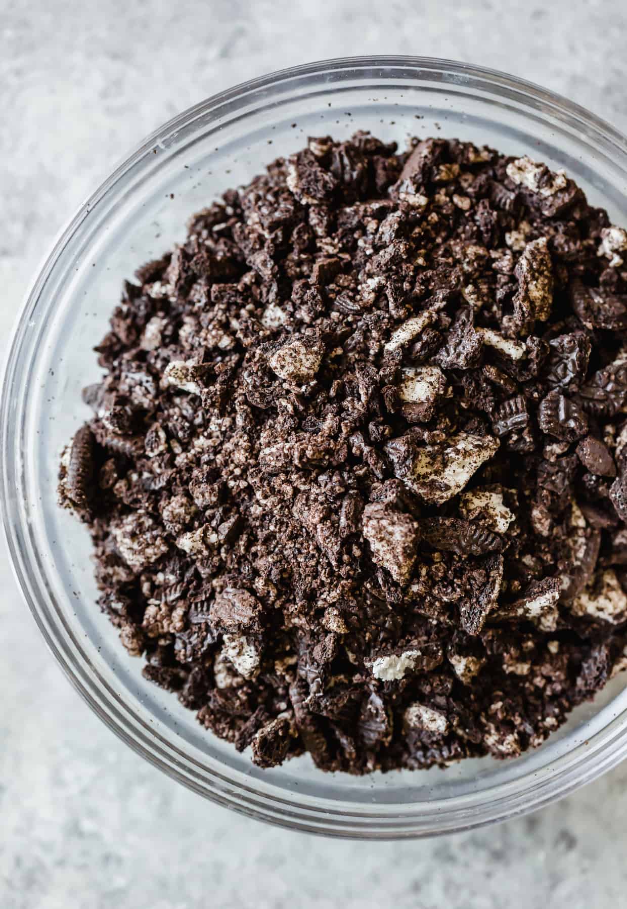 A glass bowl with crushed and chopped Oreos.