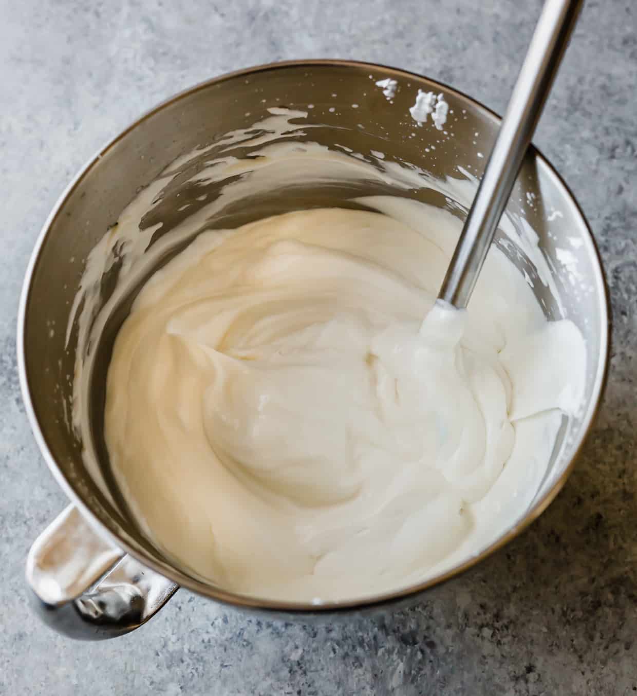 A metal bowl with freshly whipped cream and sweetened condensed milk creamed together.