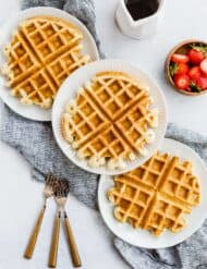 Three buttermilk waffles with three forks to the side.