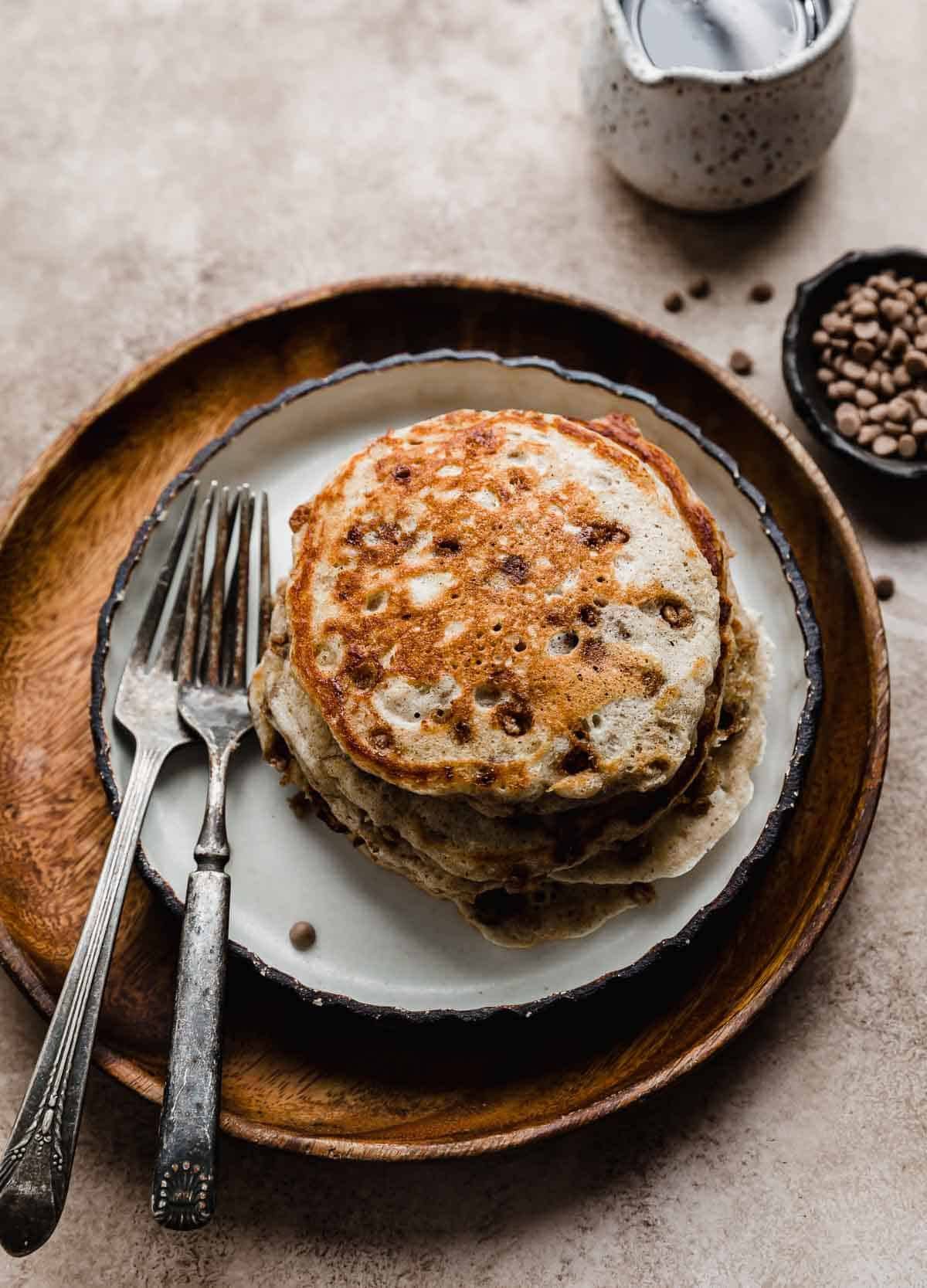 A stack of four Cinnamon Chip Pancakes on a brown wooden plate.