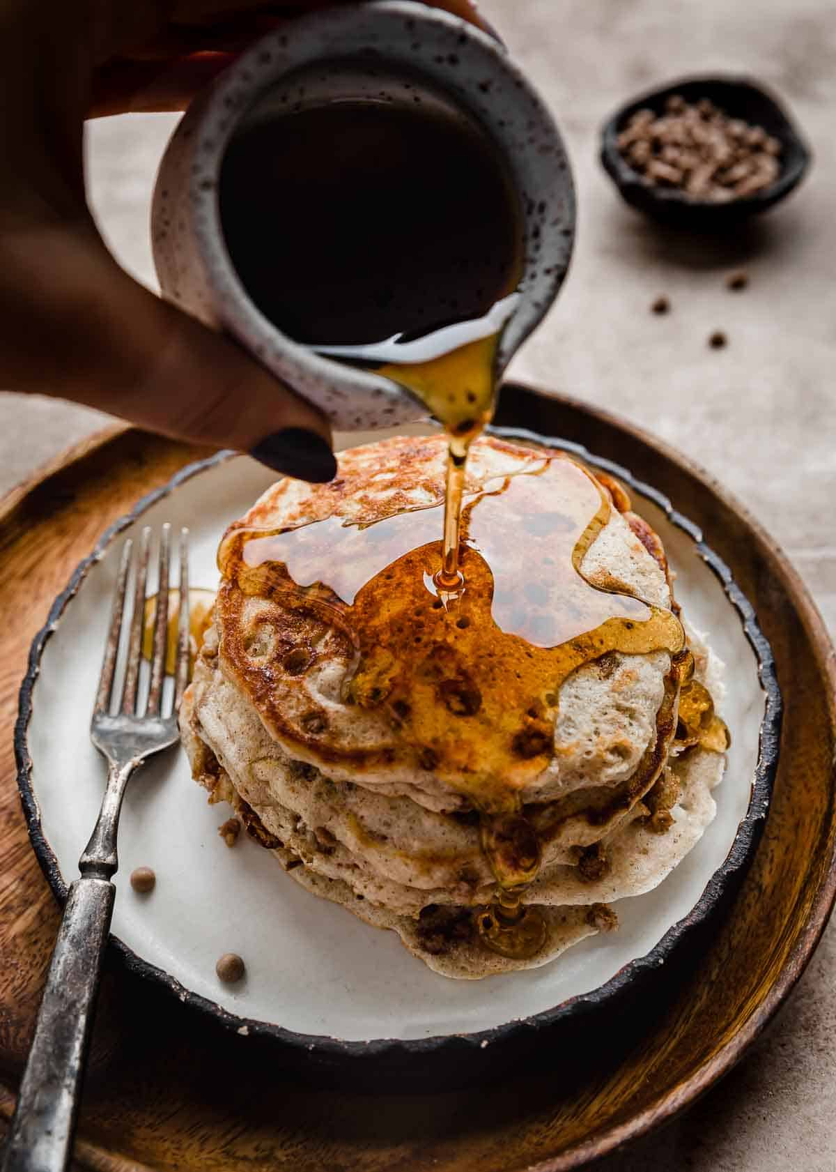Maple syrup being poured overtop a stack of Cinnamon Chip Pancakes.