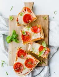 Overhead view of French Bread Pizza with pepperoni on top and a basil garnish.