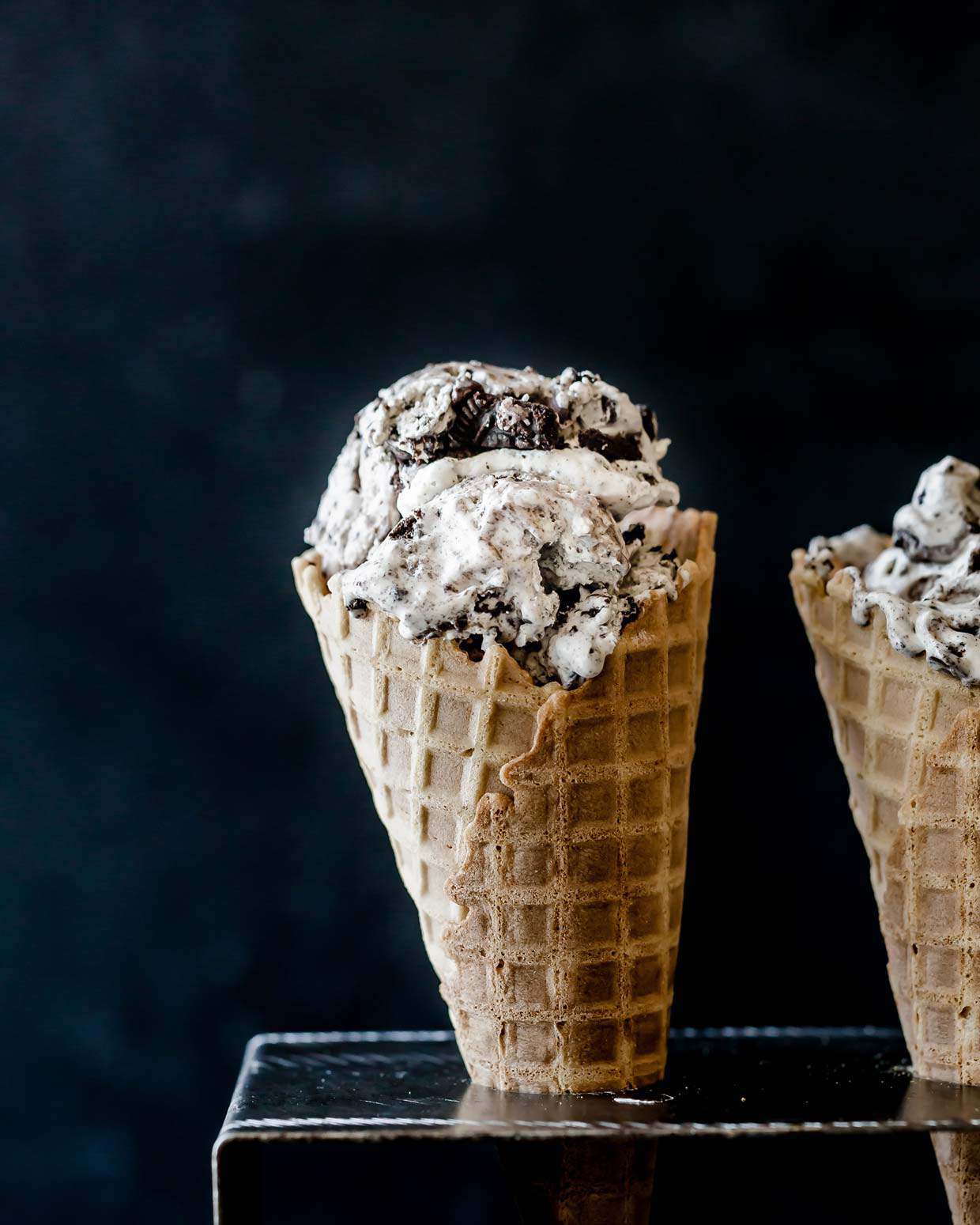 Oreo Ice Cream in a waffle cone against a black background.