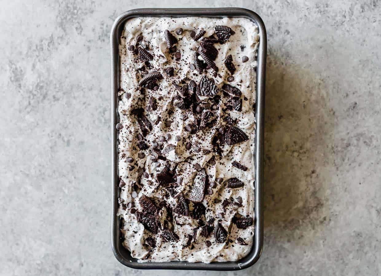 A rectangular bread pan filled with Oreo Ice Cream and topped with crushed Oreos and mini chocolate chips.