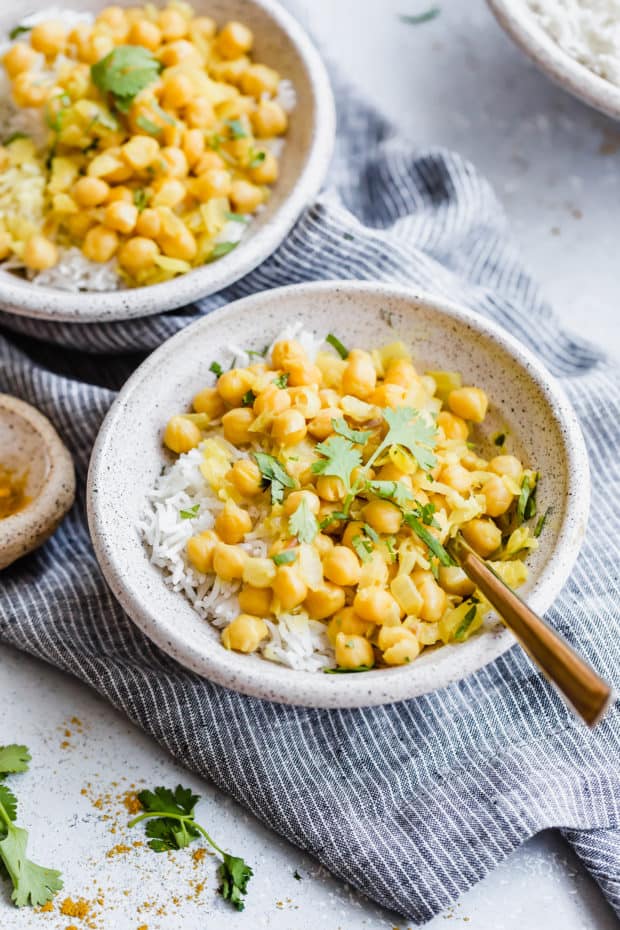 A bowl of rice topped with chickpea curry and cilantro for garnish.