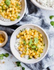 Overhead photo of 2 bowls filled with rice and chickpea curry, cilantro for garnish.