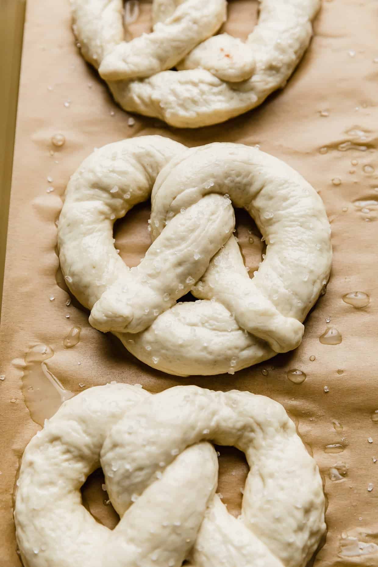 A homemade pretzel on a baking sheet prior to baking