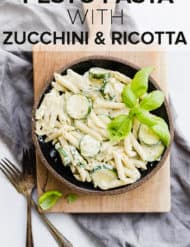 Delicious creamy summer pesto pasta with sliced zucchini and fresh basil for garnish.