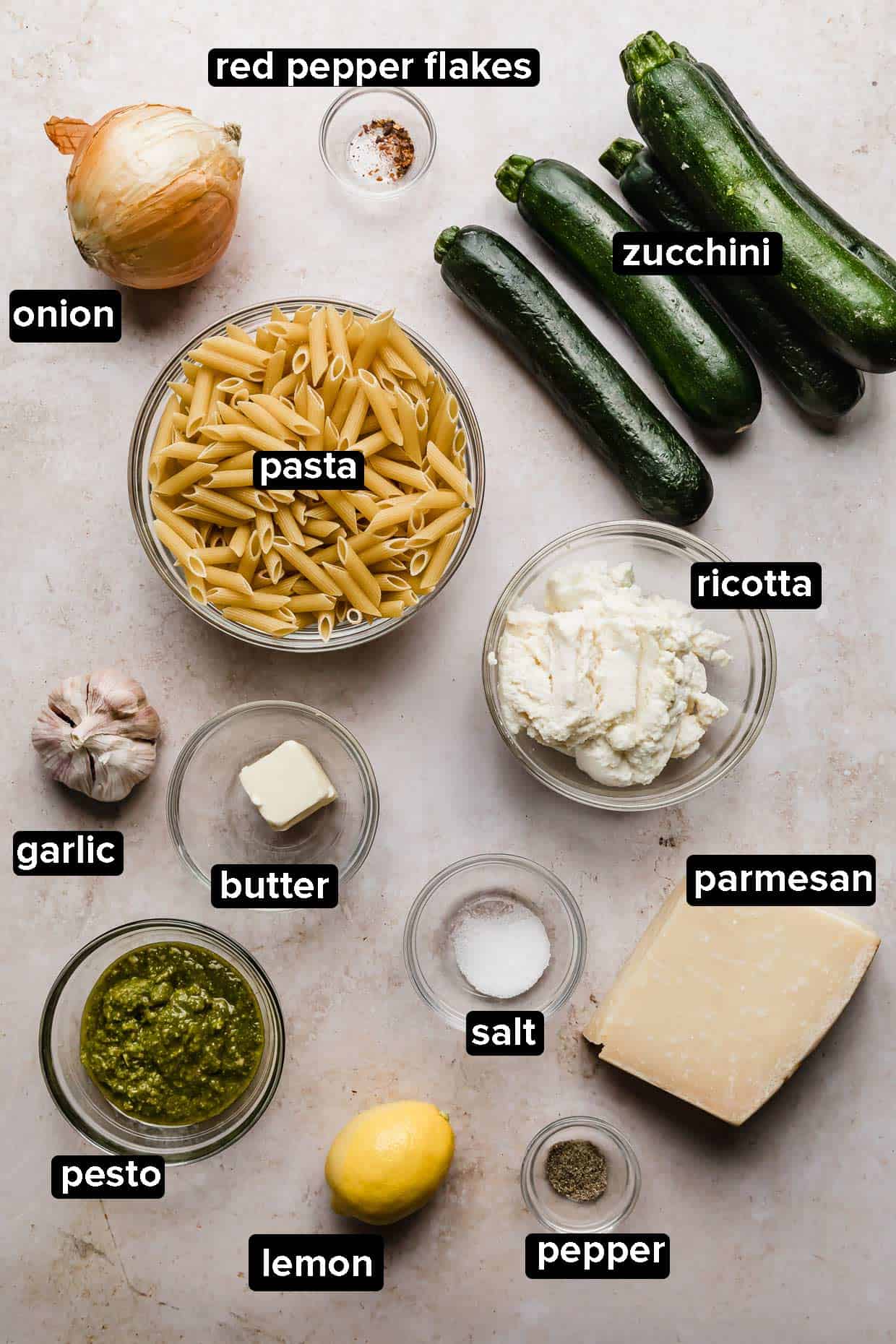 Ingredients for making summer zucchini pasta with ricotta and basil on a cream background.