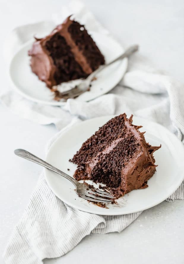 Two slices of double layered chocolate cake on a white plate, with a fork on the plate.