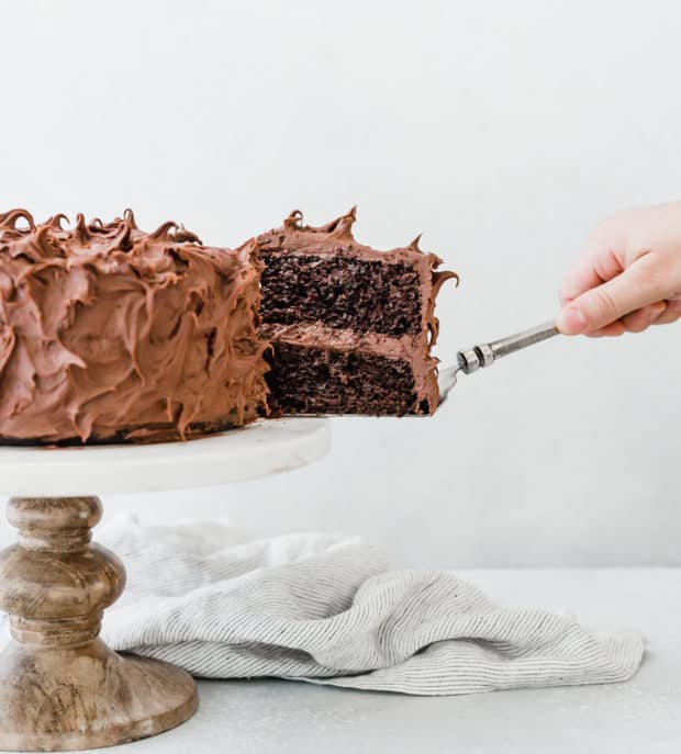 A slice of double chocolate cake being taken out of the cake.