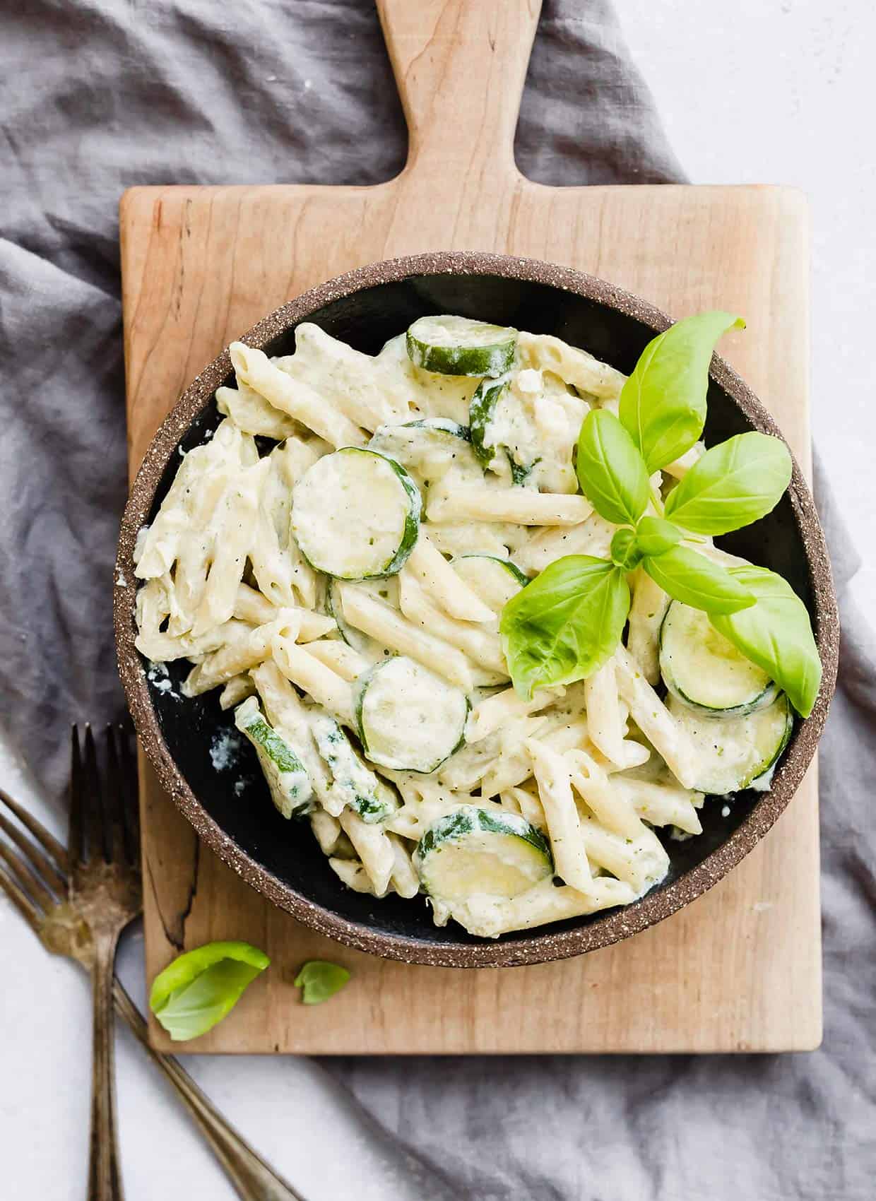 A black bowl with Summer Zucchini pasta with ricotta and basil. 