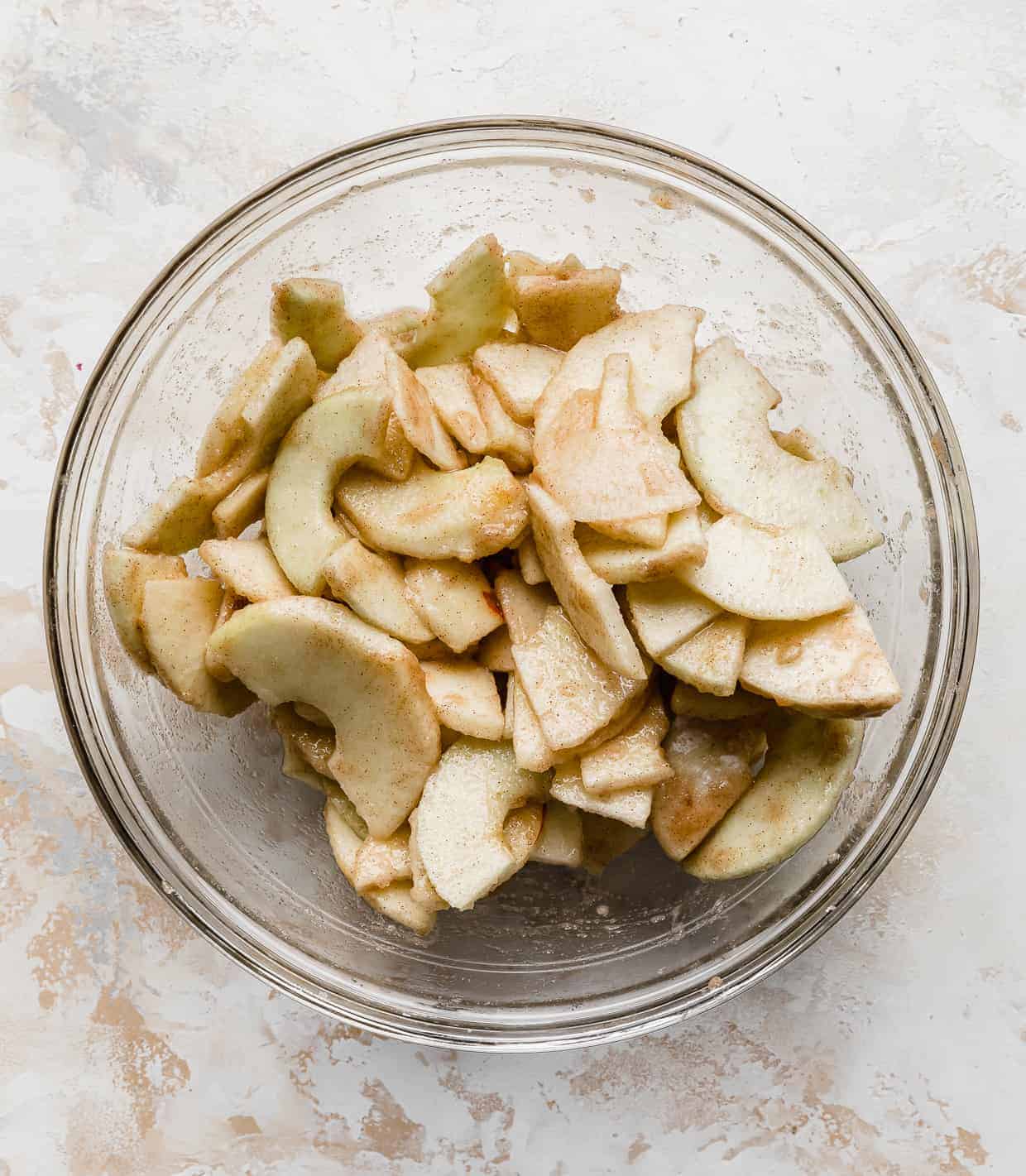 Cinnamon sugar topped sliced apples in a glass bowl for making Easy Apple Crisp.