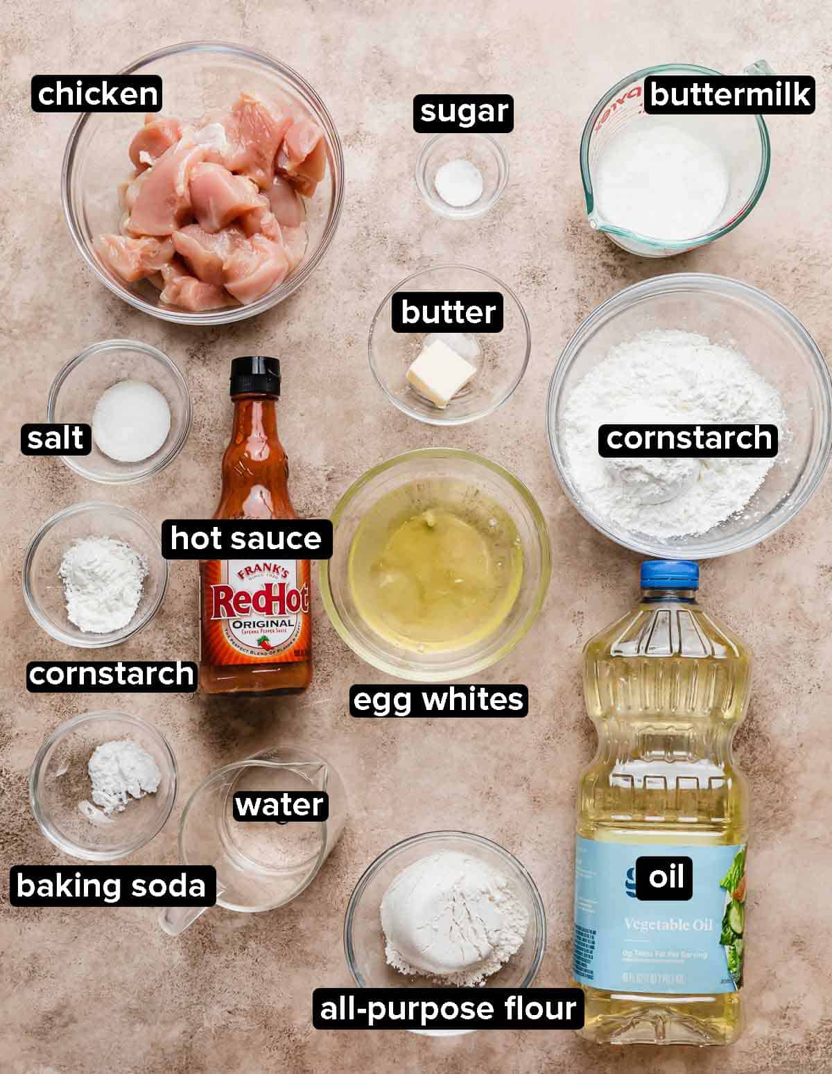 Buffalo Chicken Bites ingredients portioned into glass bowls on a light beige background.