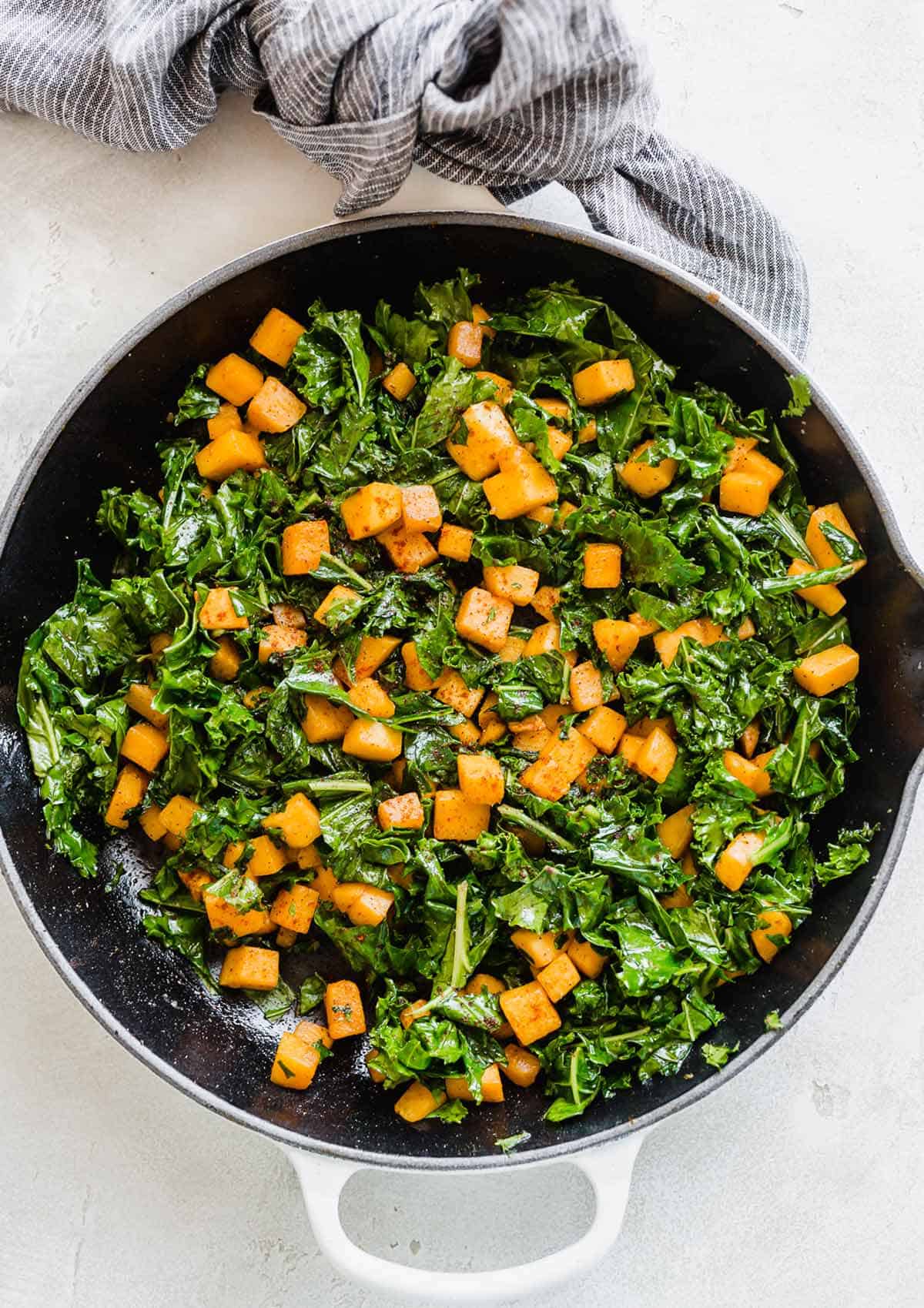 Overhead photo of Butternut Squash and Kale in a skillet on a white background.