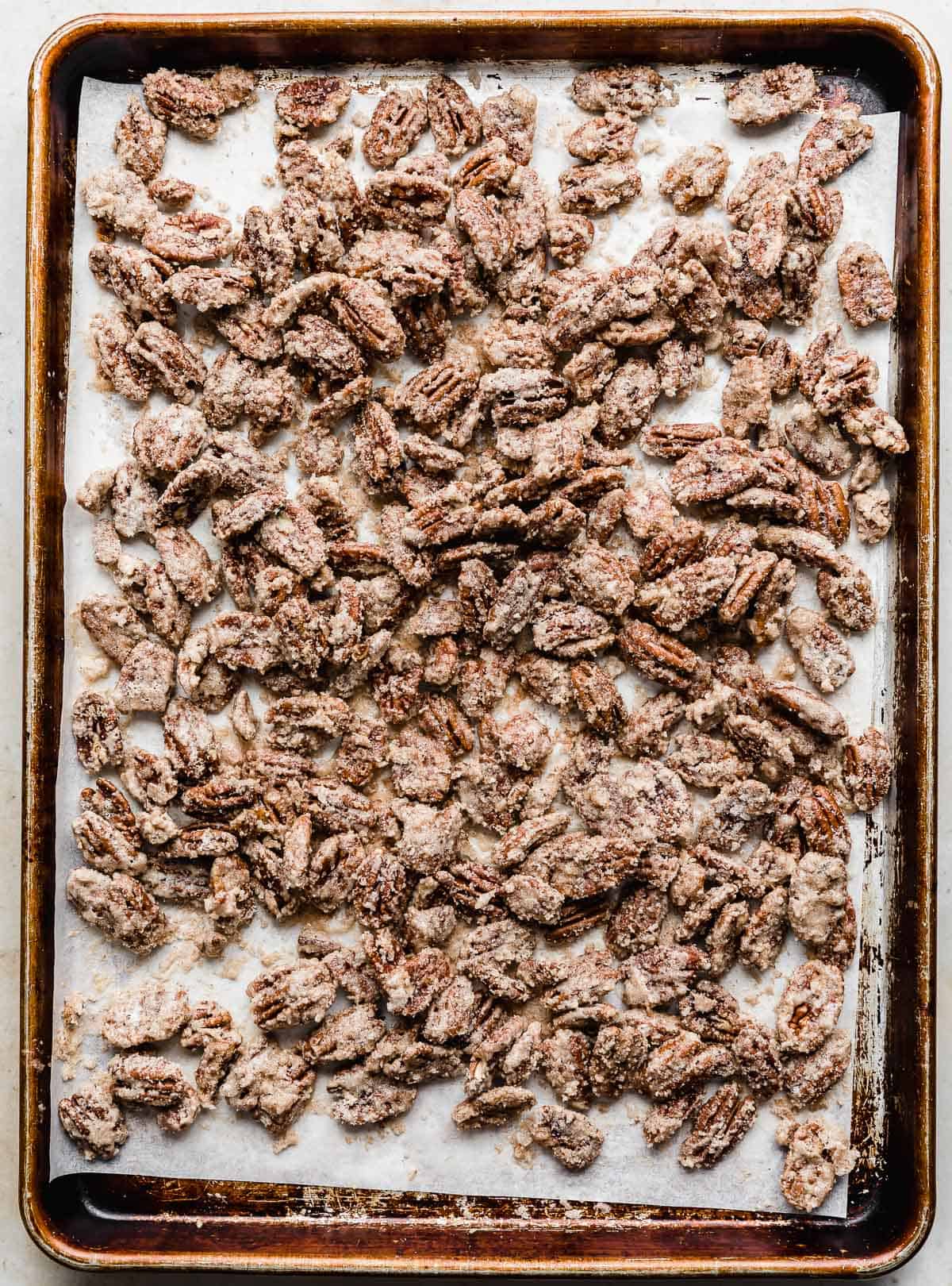 Baking sheet with Candied Pecans spread on it.