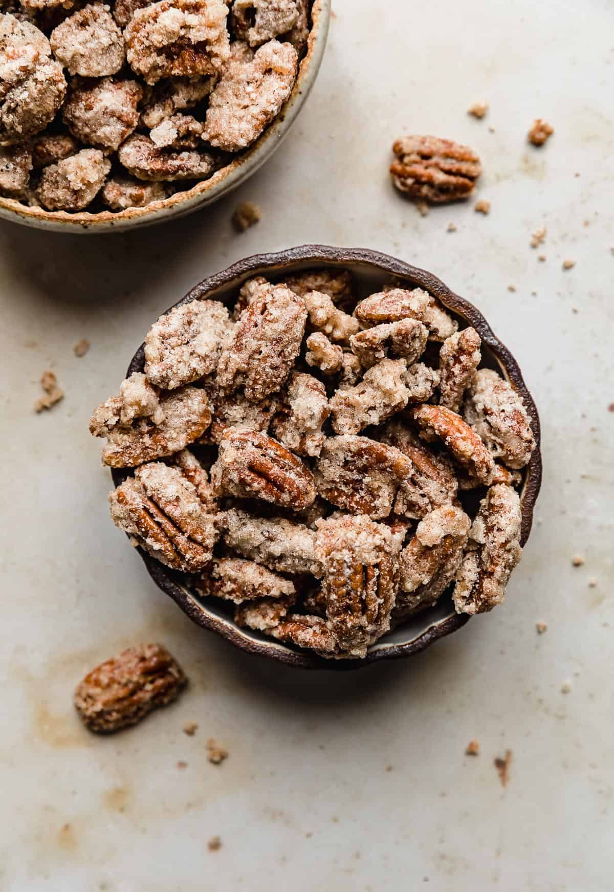 Two bowls full of sugared candied pecans.