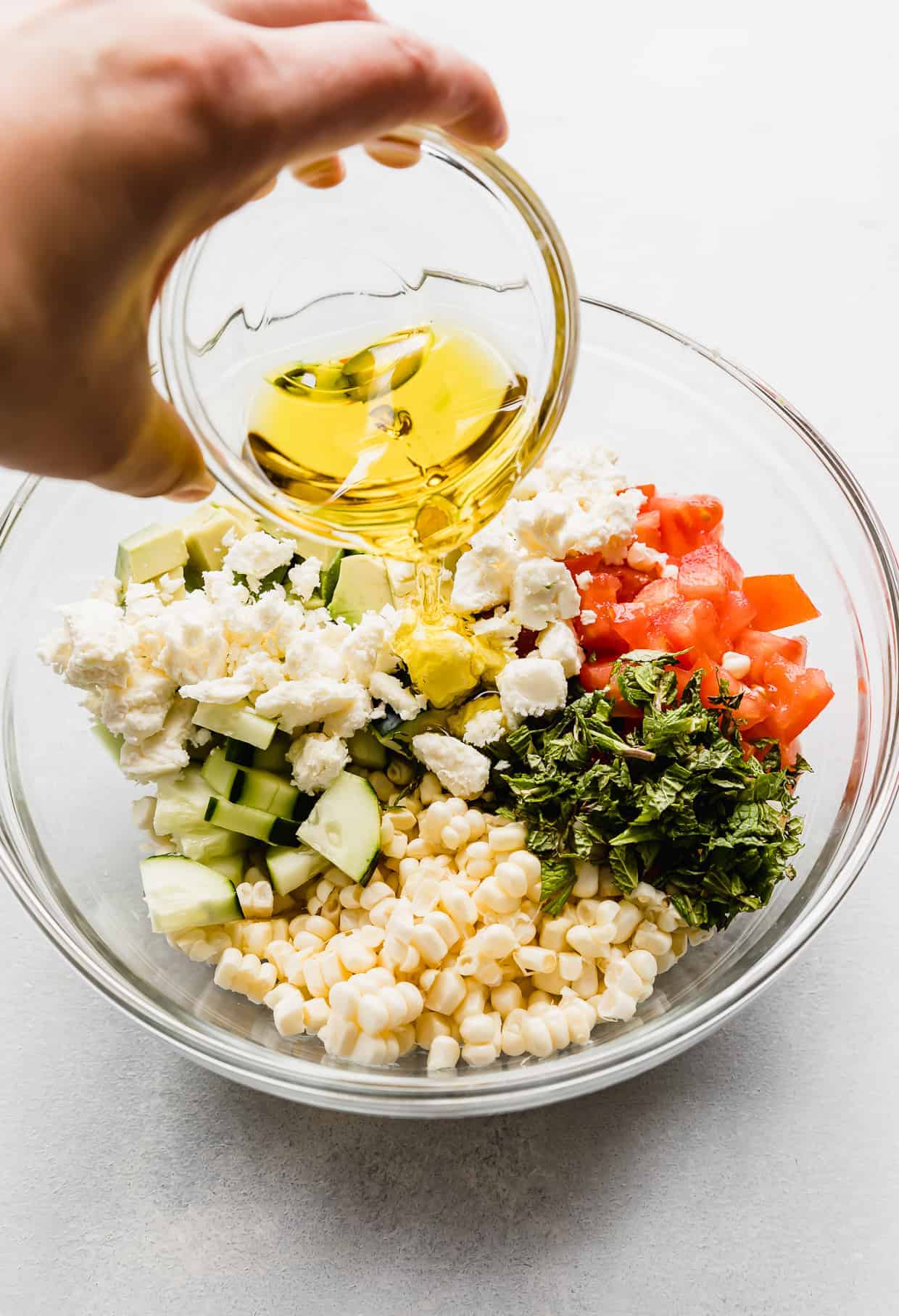 Olive oil being poured overtop of Feta Corn Salad.