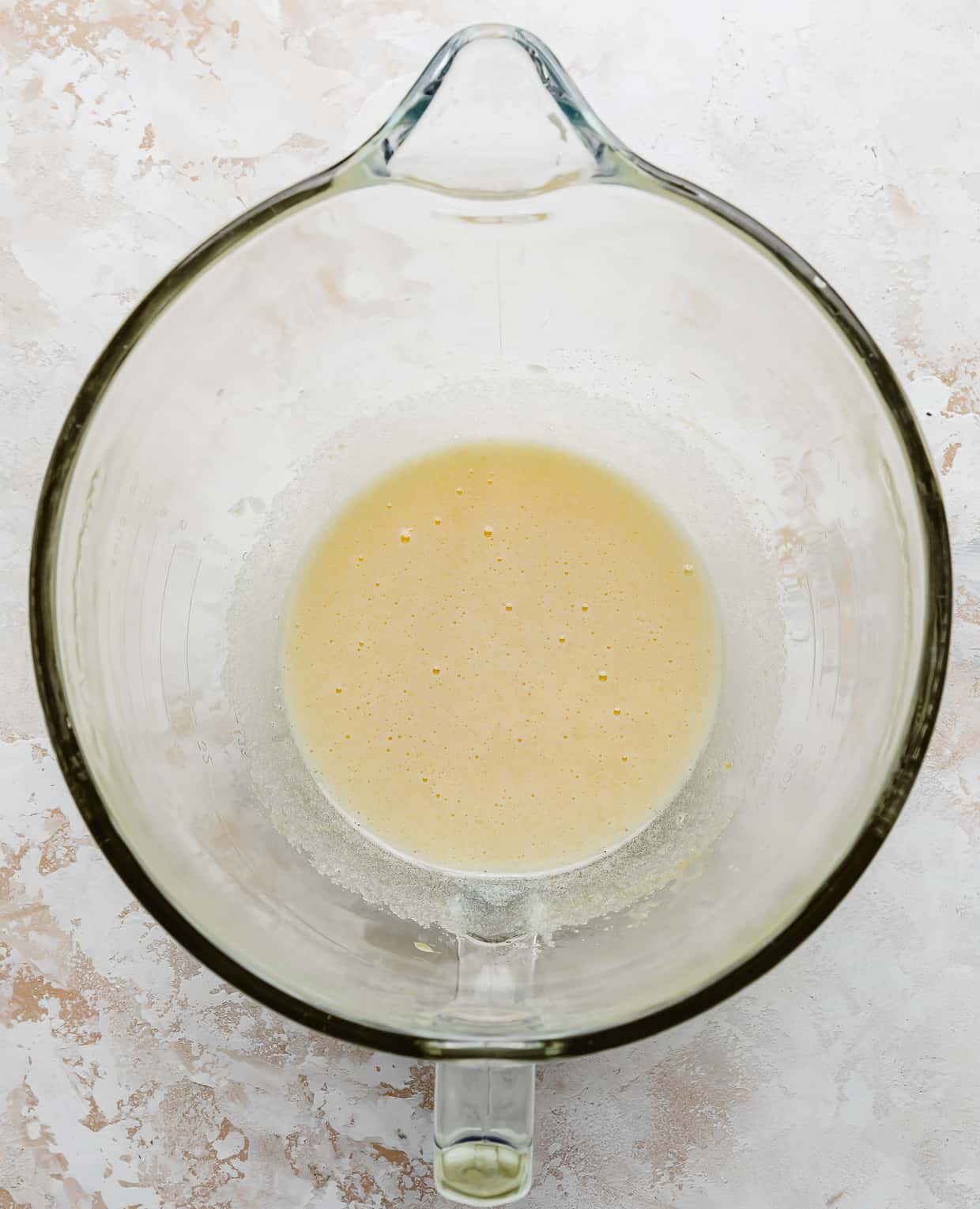 A light yellow wet mixture in a glass mixing bowl.