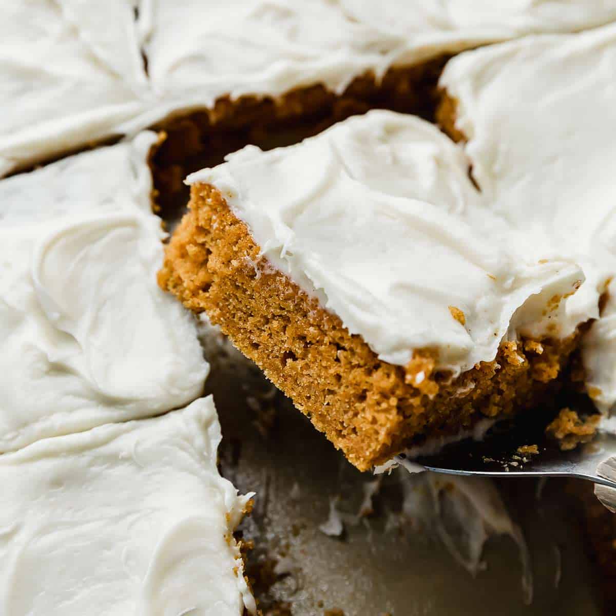 Libby's Pumpkin Bars with cream cheese frosting cut into a square, balancing on a metal spatula.