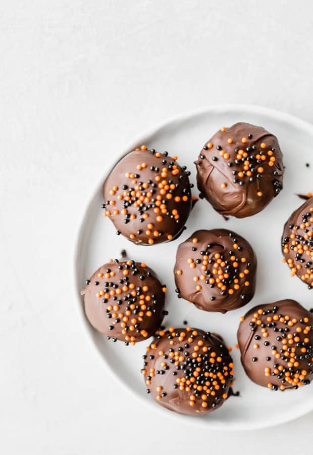 Oreo balls dipped in dark chocolate and covered in orange and black sprinkles.
