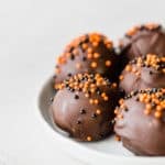 Oreo balls covered in dark chocolate and sprinkled with orange and black ball sprinkles.