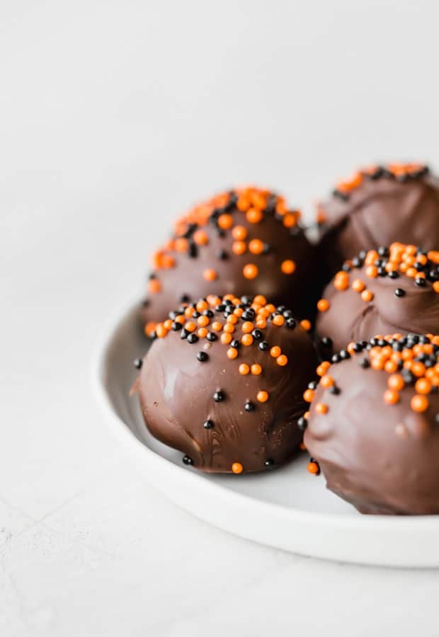 Oreo balls covered in dark chocolate and sprinkled with orange and black ball sprinkles.