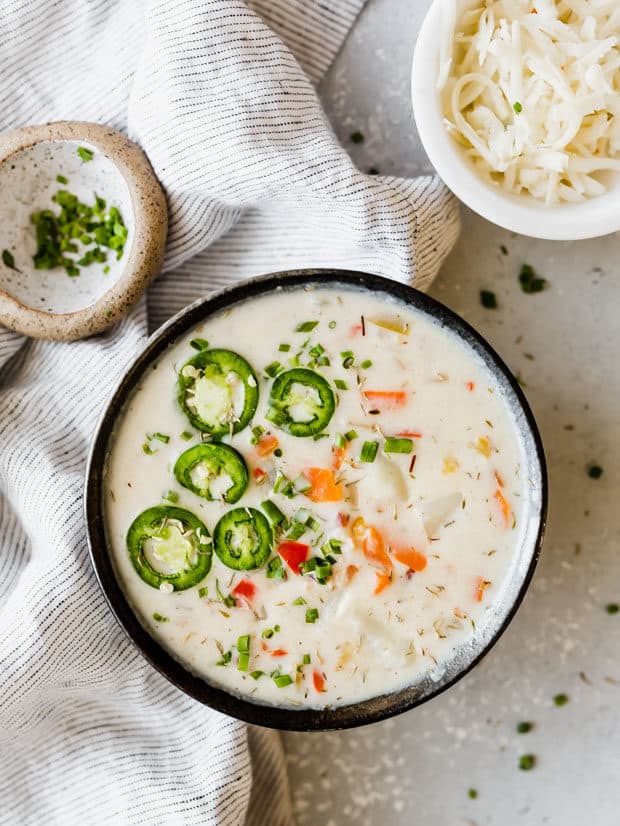 Potato pepper jack soup with a spoon in the bowl and sliced jalapeños for garnish.