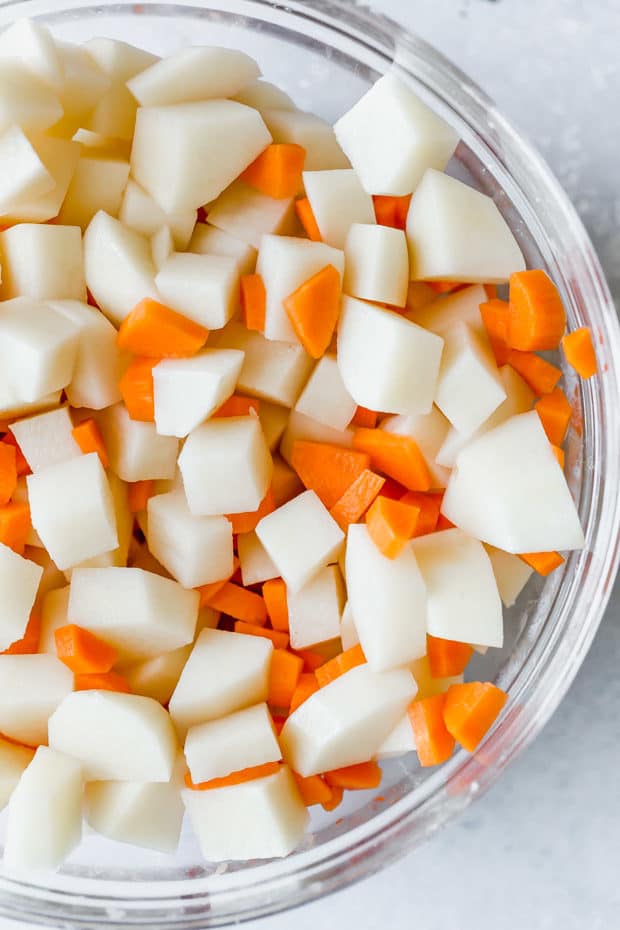 Diced potatoes and carrots in a glass bowl.