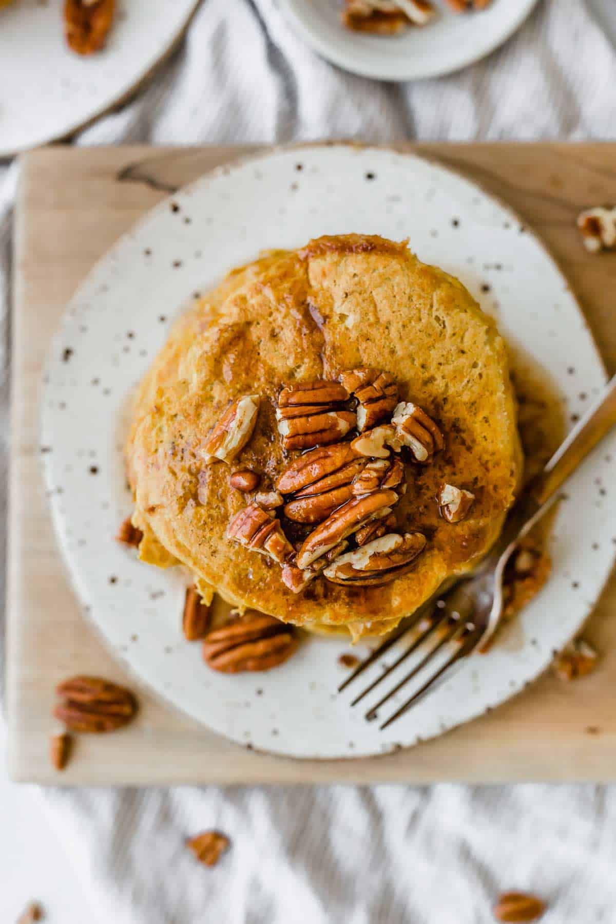 Overheard photo of fluffy pumpkin pancakes topped with chopped pecans.