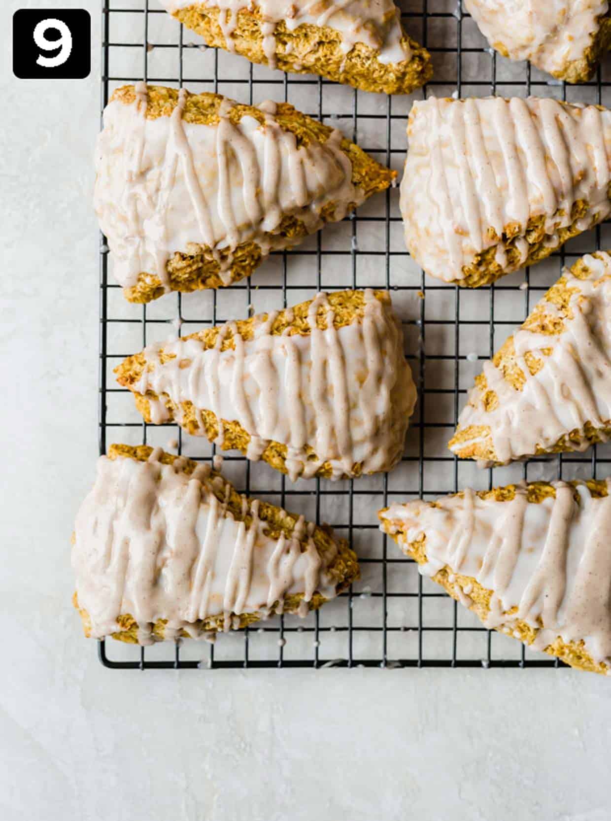 Pumpkin scones topped with a spiced glaze, on a wire cooling rack.